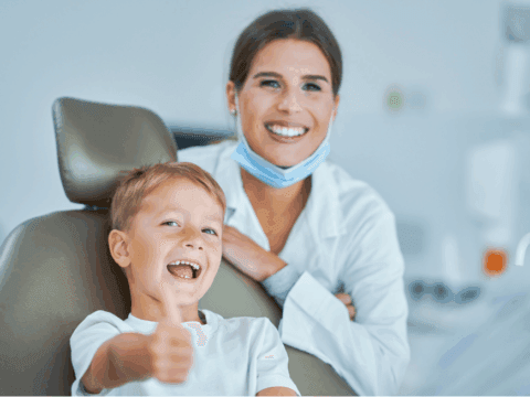Little boy sitting in the dentists office, smiling with confidence with our doctor