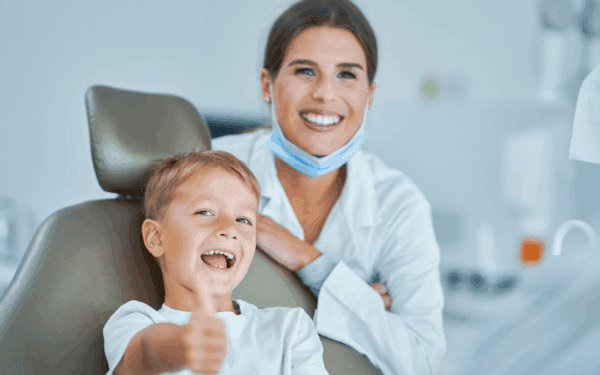 Little boy sitting in the dentists office, smiling with confidence with our doctor